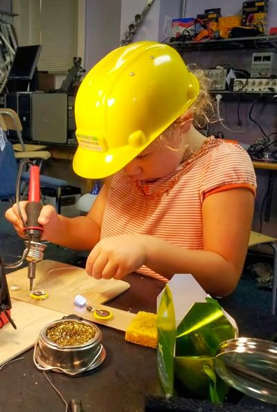 Girl soldering while wearing safety gear