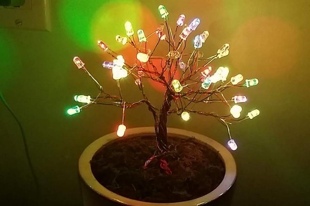 Handmade LED tree sculpture with multicolored lights glowing in a decorative pot, created by a student learning electronics
