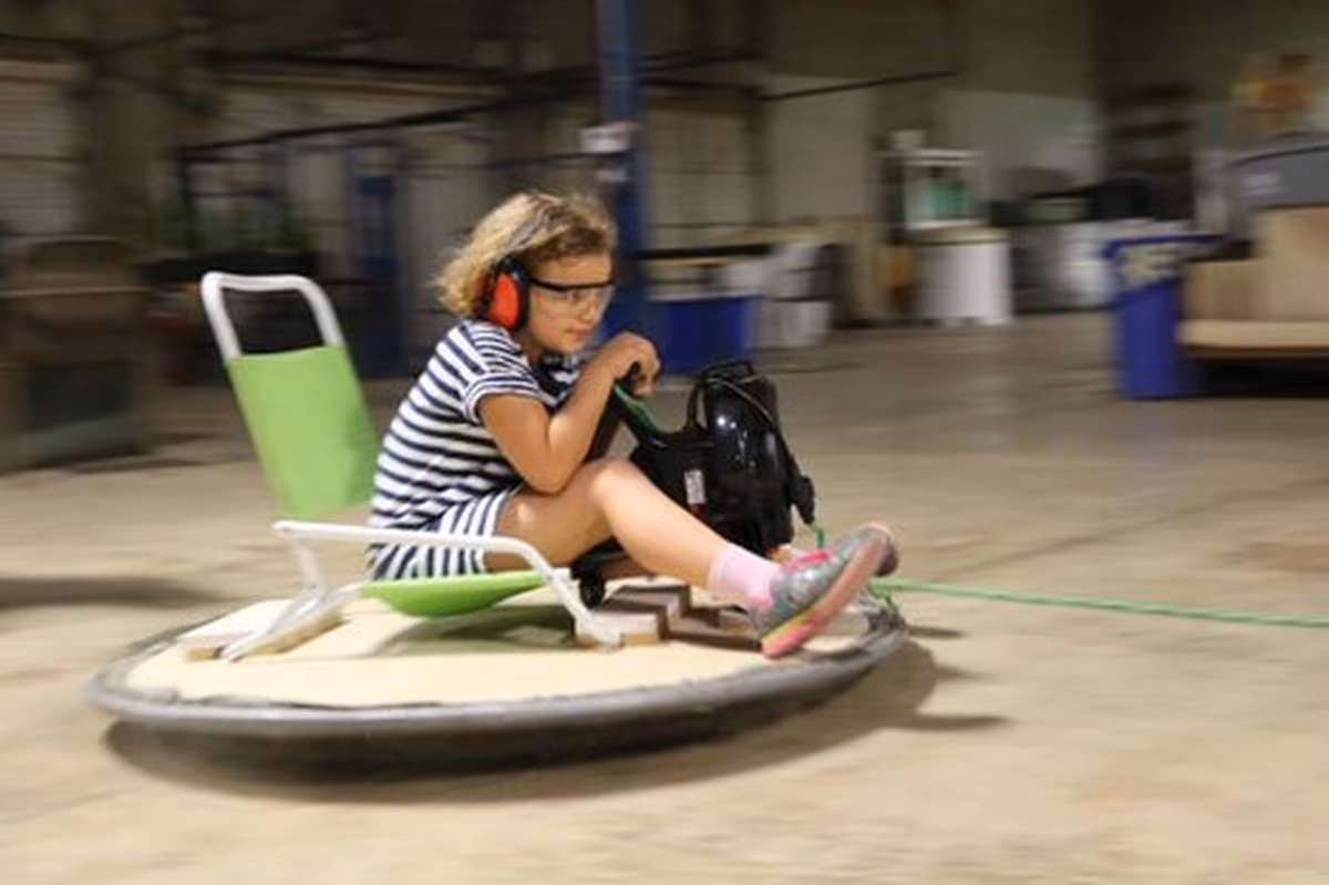 Kid riding a maker-built hovercraft