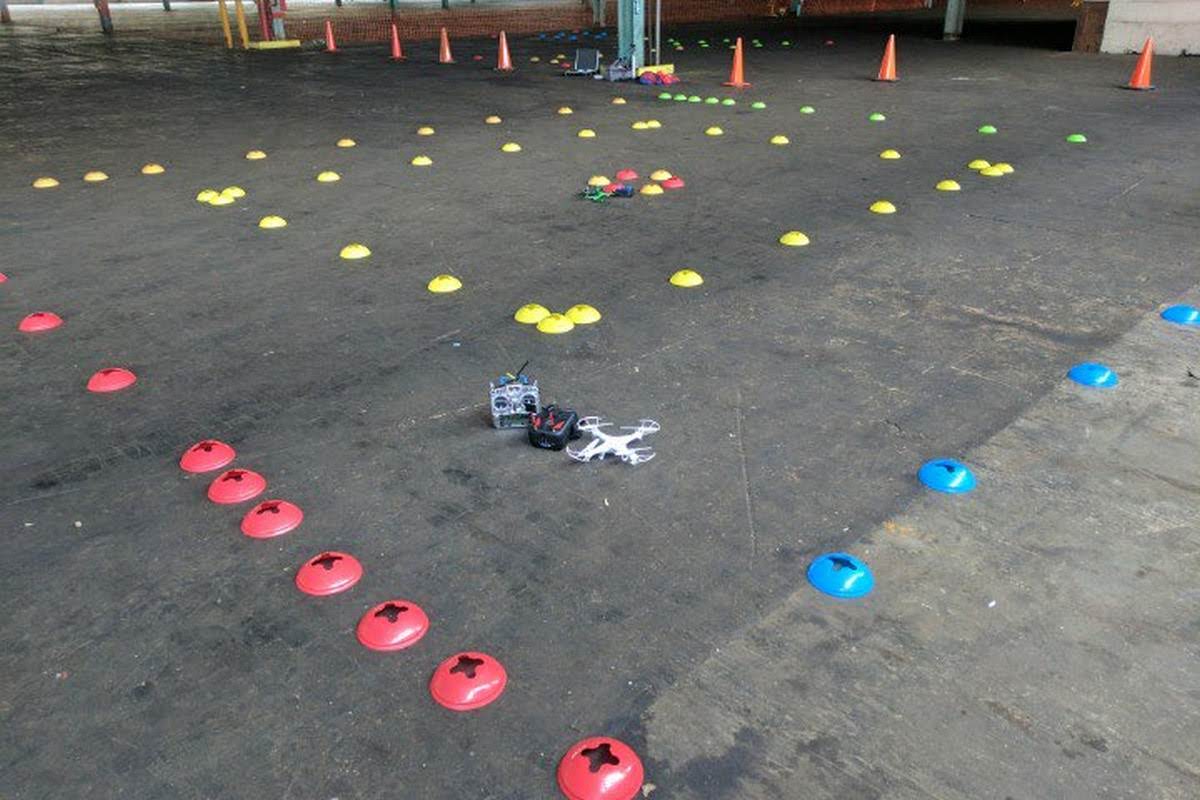 Drone racing course set up with colorful cones marking the flight path and a quadcopter with controller ready for practice